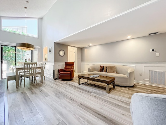 living room with light wood-type flooring and high vaulted ceiling