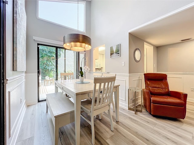 dining area with a towering ceiling and light wood-type flooring