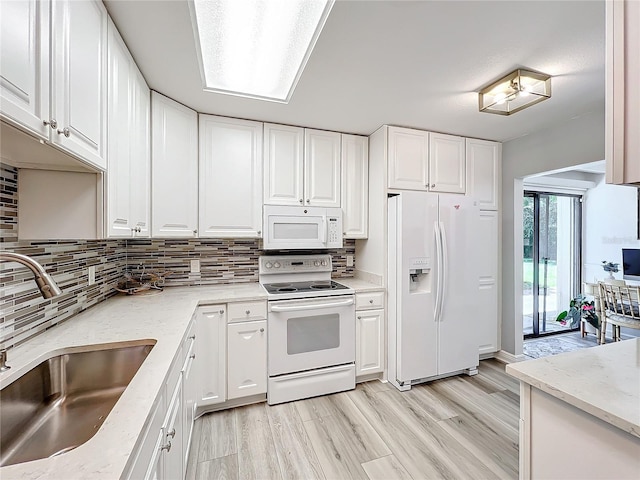 kitchen with white cabinets, white appliances, sink, and light hardwood / wood-style flooring