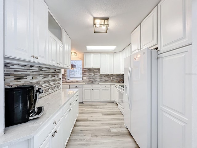 kitchen featuring white cabinetry, sink, white appliances, and light hardwood / wood-style flooring