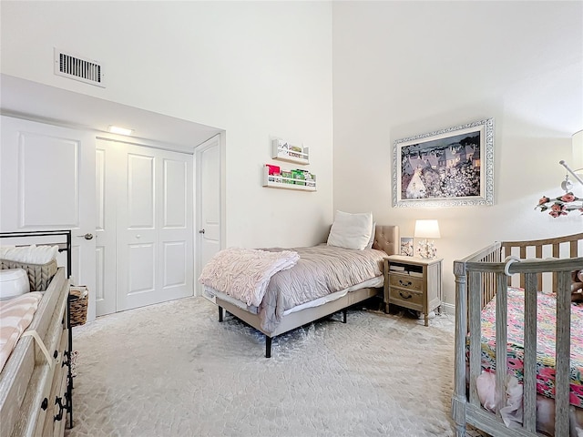 carpeted bedroom with a towering ceiling and a closet