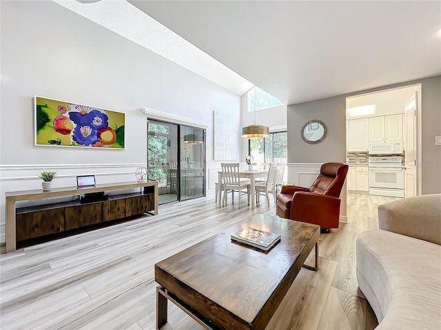 living room with light wood-type flooring and high vaulted ceiling