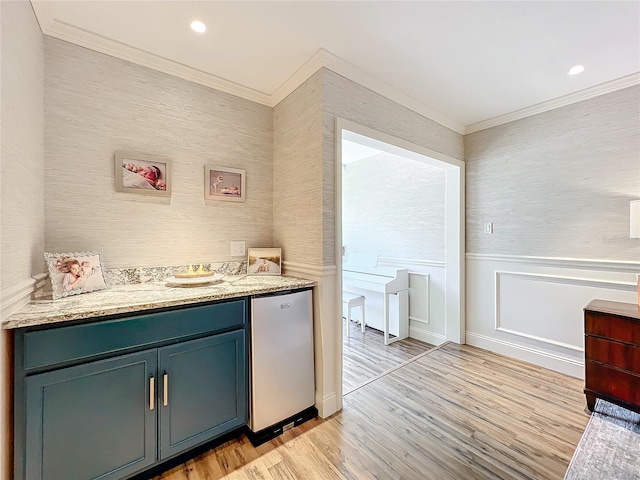 bar featuring stainless steel refrigerator, light stone countertops, light hardwood / wood-style floors, and ornamental molding