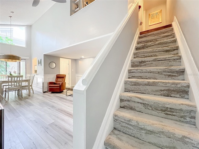 stairway featuring wood-type flooring and a high ceiling