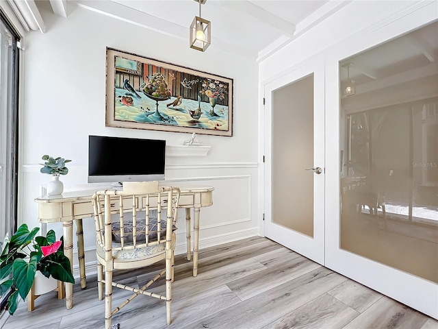 home office with beam ceiling, light wood-type flooring, and french doors