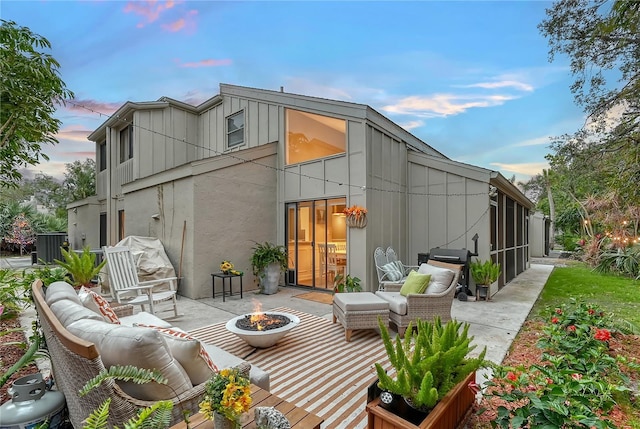 back house at dusk featuring an outdoor living space with a fire pit and a patio