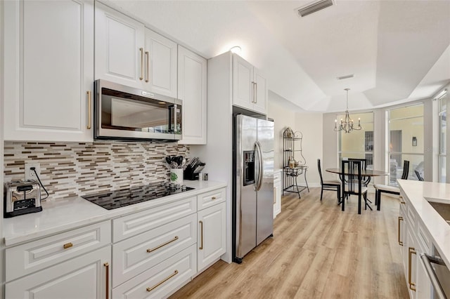 kitchen with stainless steel appliances, an inviting chandelier, light hardwood / wood-style flooring, pendant lighting, and white cabinets