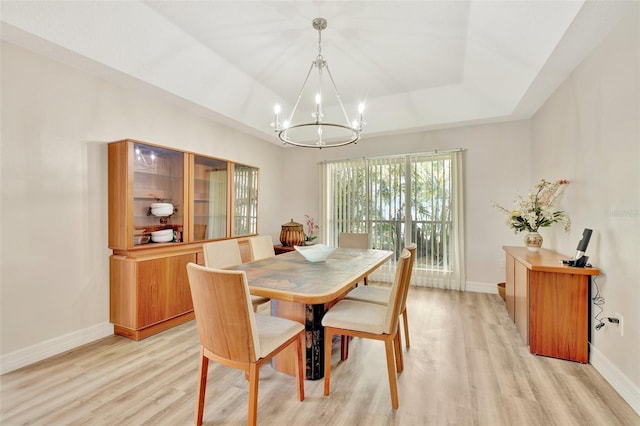 dining room with light hardwood / wood-style floors, a tray ceiling, and a chandelier