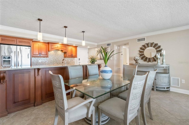 tiled dining area with a textured ceiling, ornamental molding, and sink