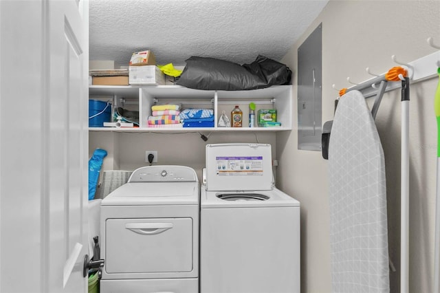 clothes washing area featuring washing machine and dryer, electric panel, and a textured ceiling