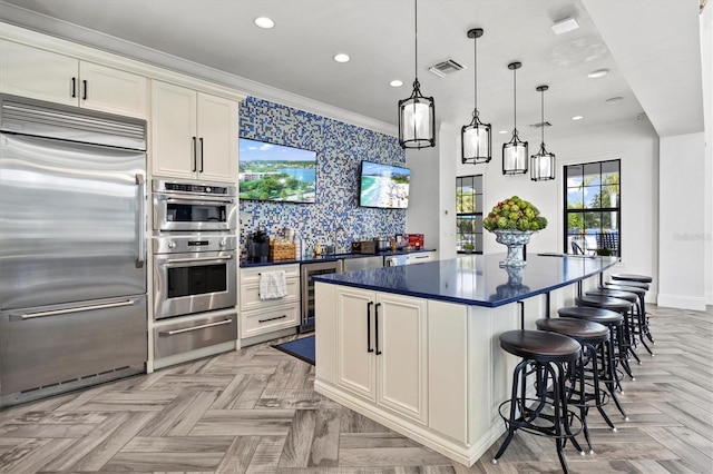 kitchen featuring appliances with stainless steel finishes, white cabinets, a kitchen island, pendant lighting, and light parquet flooring