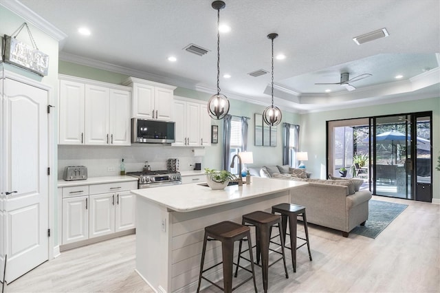 kitchen with open floor plan, stainless steel appliances, a center island with sink, and visible vents