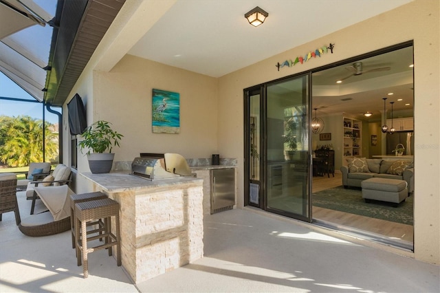 view of patio / terrace featuring glass enclosure, outdoor dry bar, and an outdoor kitchen