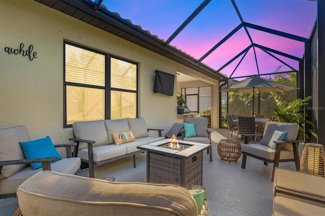 patio terrace at dusk with outdoor dining space, glass enclosure, and an outdoor living space with a fire pit