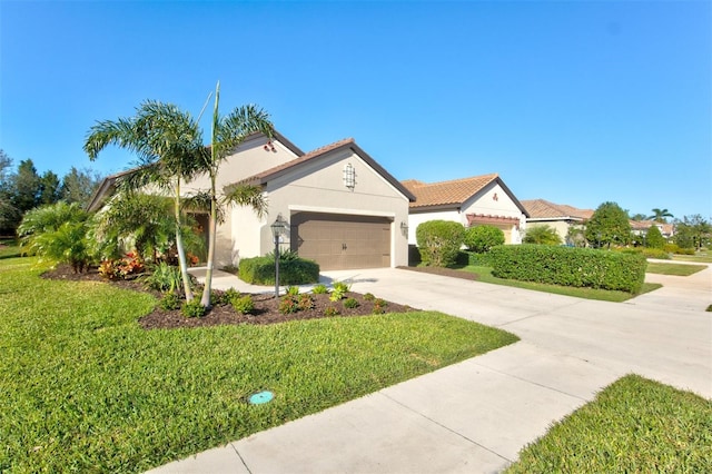 mediterranean / spanish-style house featuring a front yard, driveway, an attached garage, and stucco siding