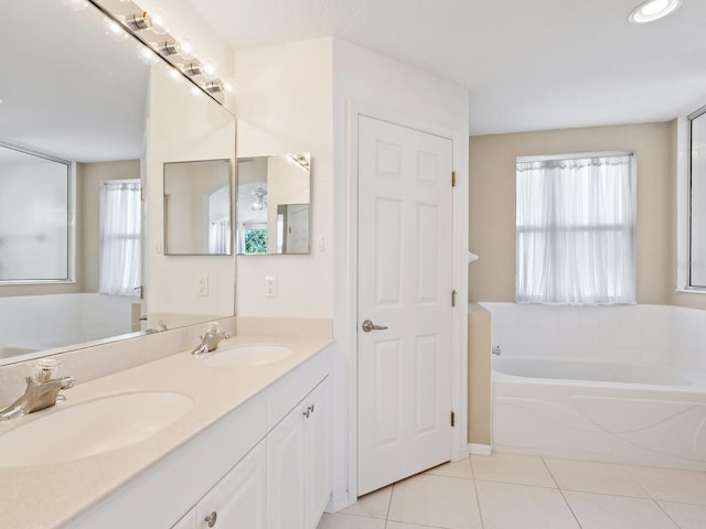 bathroom with tile patterned floors, a washtub, and vanity