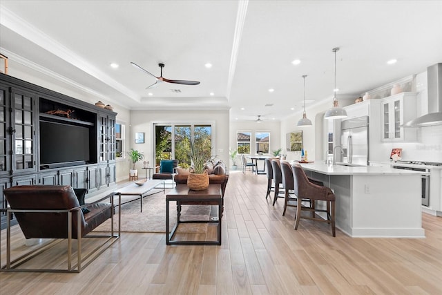 living room featuring light hardwood / wood-style flooring, ceiling fan, and ornamental molding