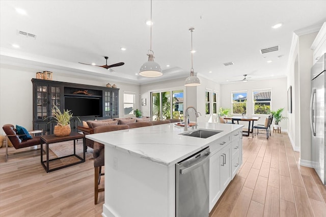 kitchen with appliances with stainless steel finishes, ceiling fan, sink, white cabinetry, and hanging light fixtures