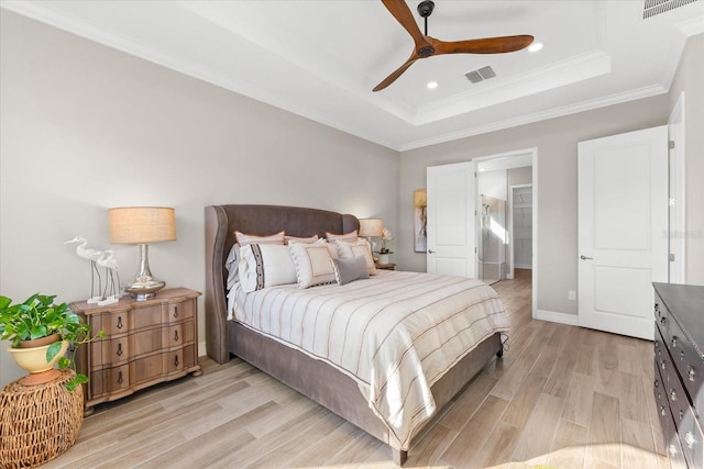 bedroom featuring a tray ceiling, ceiling fan, crown molding, and light hardwood / wood-style floors