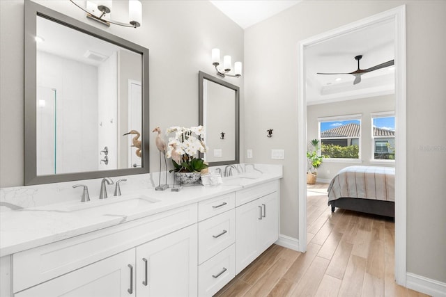 bathroom with vanity, hardwood / wood-style flooring, a raised ceiling, and ceiling fan