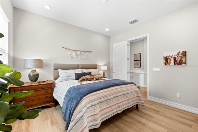 bedroom featuring ensuite bathroom, light wood-type flooring, and multiple windows