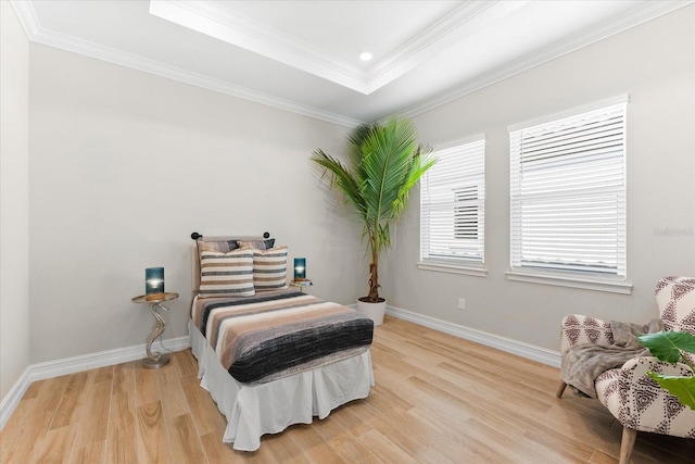 bedroom with hardwood / wood-style flooring, a tray ceiling, and crown molding