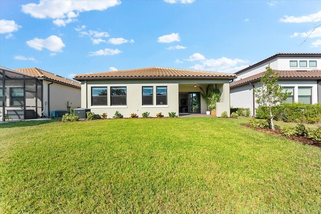 rear view of property with glass enclosure, ceiling fan, a yard, and central AC unit