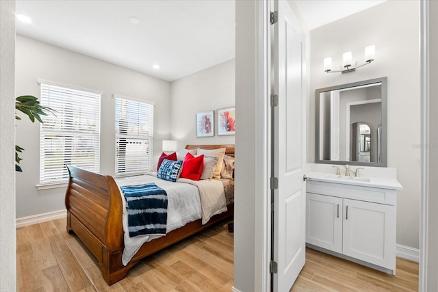 bedroom featuring light wood finished floors, a sink, and baseboards