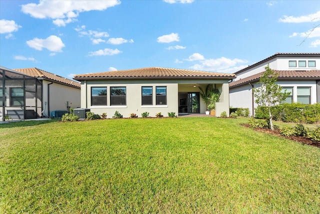 back of property with central air condition unit, a lanai, a lawn, and stucco siding