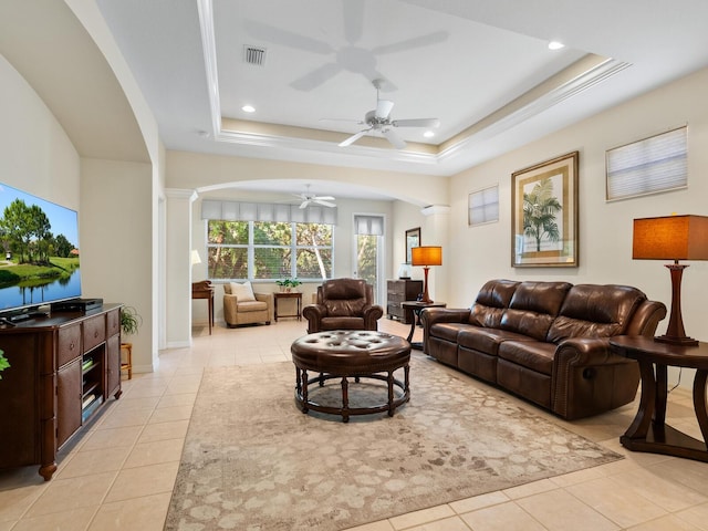 living room with ceiling fan, a raised ceiling, light tile patterned floors, and ornate columns