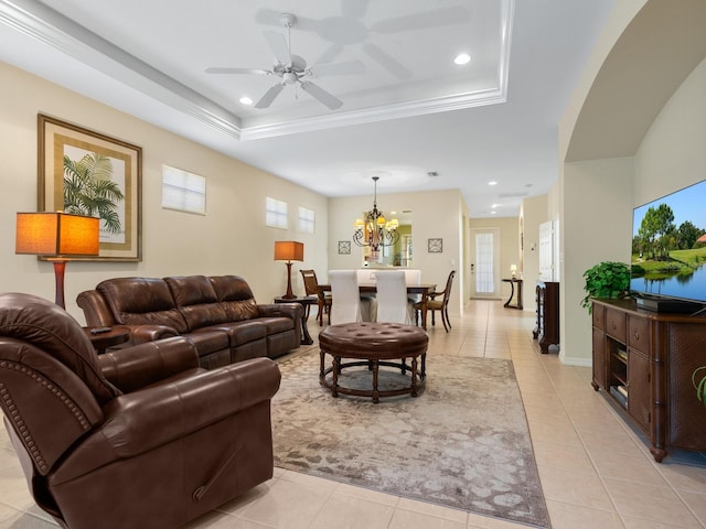 living room with light tile patterned floors, ceiling fan with notable chandelier, a tray ceiling, and crown molding