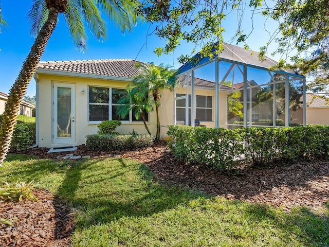 rear view of property with a lawn and a lanai