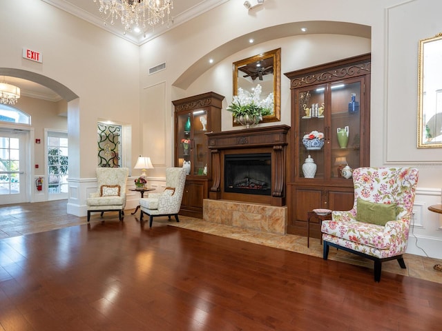 sitting room with a notable chandelier, hardwood / wood-style floors, a high ceiling, and ornamental molding