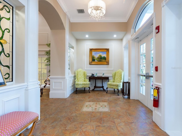 foyer featuring ornate columns, crown molding, french doors, and an inviting chandelier