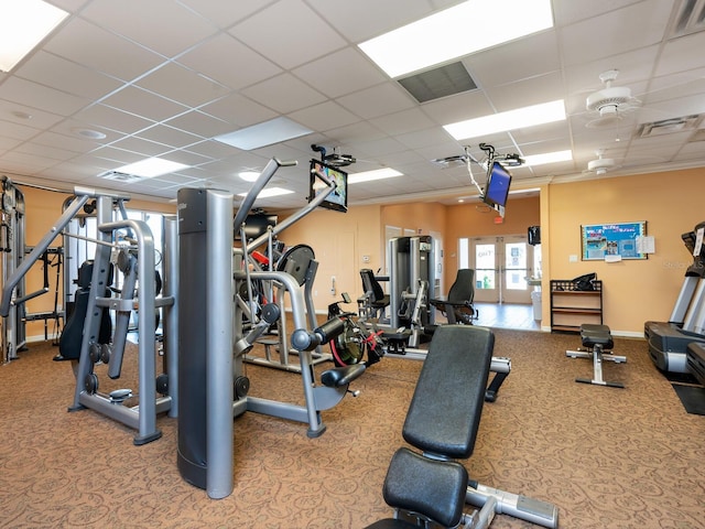 gym with crown molding, a drop ceiling, and ceiling fan