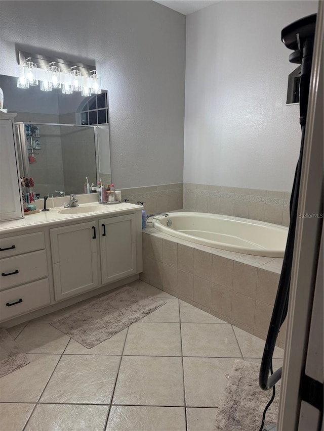 bathroom with tile patterned flooring, vanity, and tiled tub