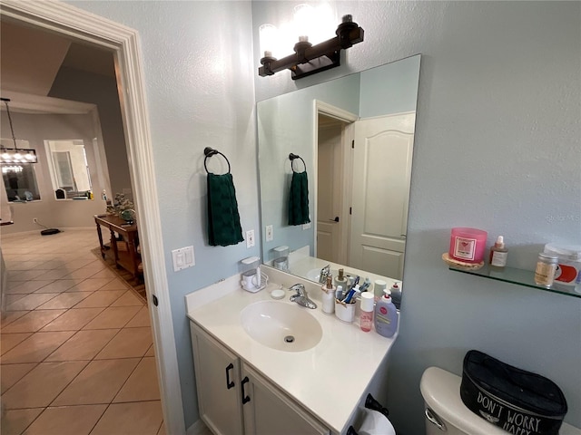 bathroom featuring tile patterned flooring, vanity, a notable chandelier, and toilet