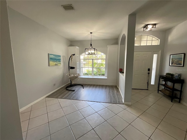 tiled foyer entrance featuring an inviting chandelier