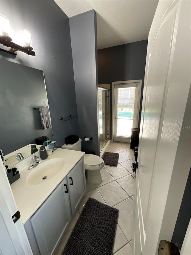 bathroom featuring tile patterned flooring, vanity, an enclosed shower, and toilet