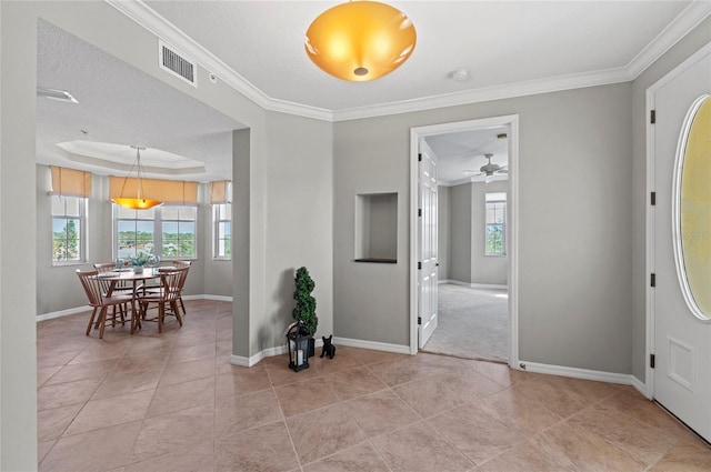 tiled entryway with a tray ceiling, ceiling fan, and ornamental molding