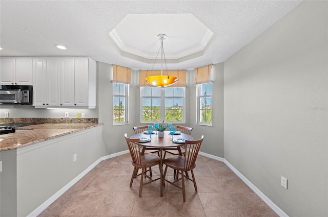 dining space featuring a textured ceiling, light tile patterned floors, crown molding, and a tray ceiling