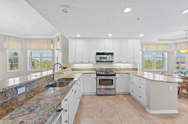 kitchen featuring sink, ornamental molding, appliances with stainless steel finishes, decorative light fixtures, and white cabinetry