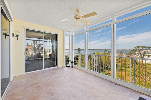 unfurnished sunroom featuring a water view and ceiling fan