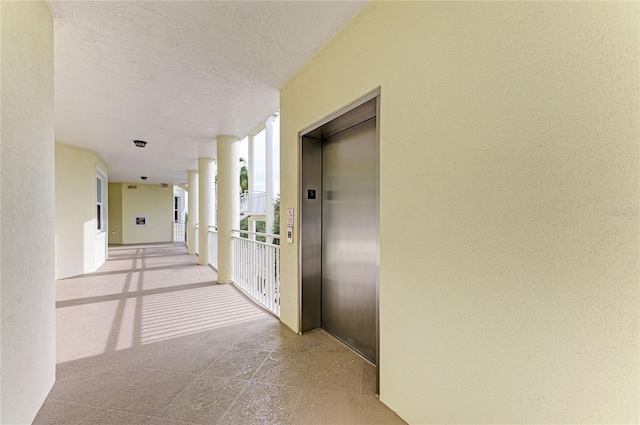 hallway with a textured ceiling and elevator