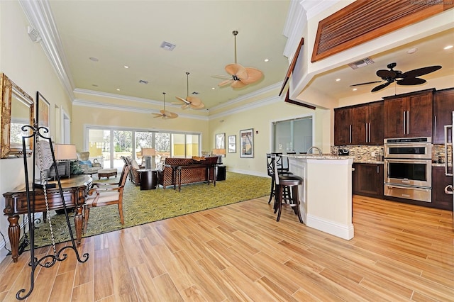 kitchen featuring dark brown cabinetry, light wood-type flooring, and crown molding