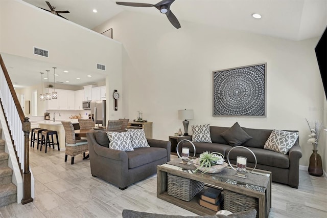 living room with sink, ceiling fan with notable chandelier, and high vaulted ceiling