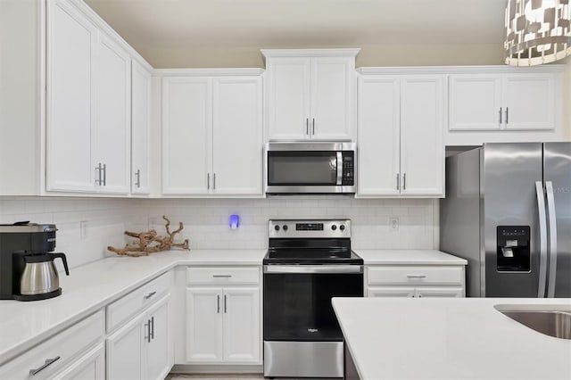 kitchen with pendant lighting, white cabinets, stainless steel appliances, and tasteful backsplash