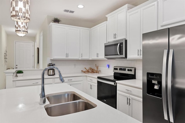 kitchen featuring appliances with stainless steel finishes, white cabinetry, hanging light fixtures, sink, and backsplash