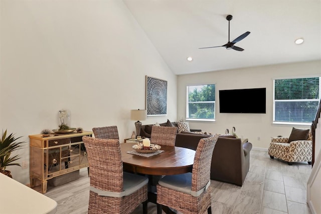 dining area with ceiling fan, high vaulted ceiling, and light hardwood / wood-style flooring