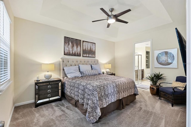 carpeted bedroom with ceiling fan, connected bathroom, and a raised ceiling